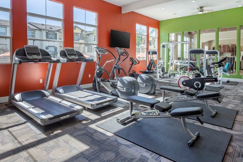a gym with cardio equipment and a flat screen tv
