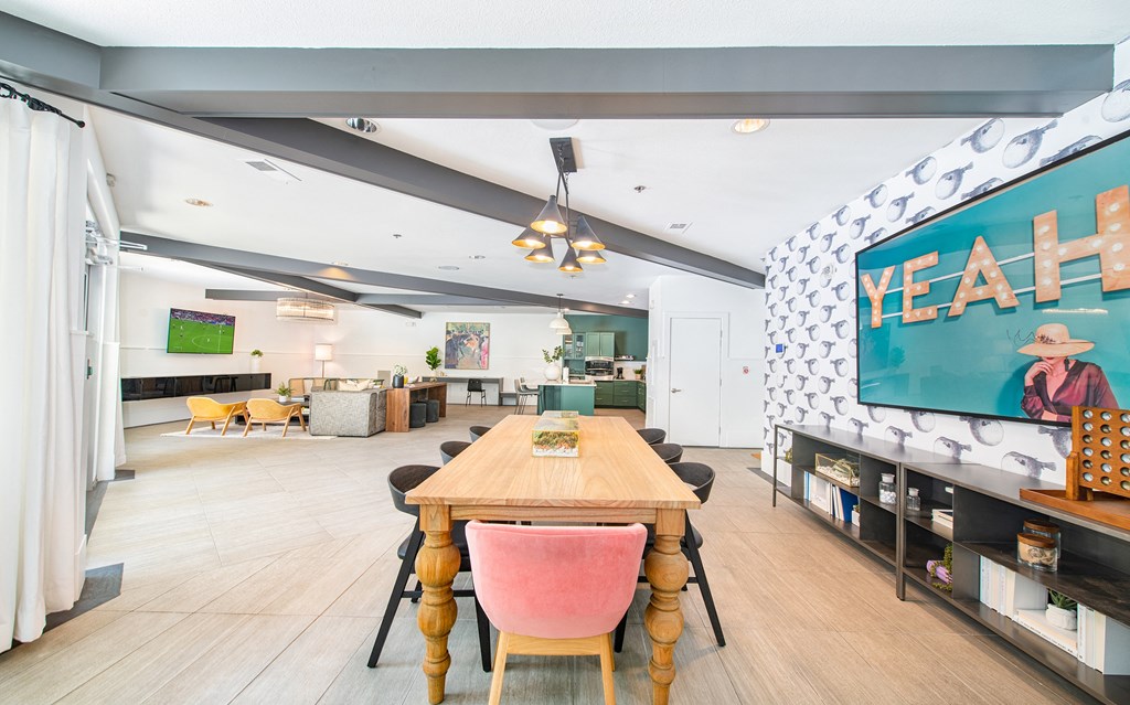 a dining room with a wooden table and chairs and a large flat screen tv on the wall