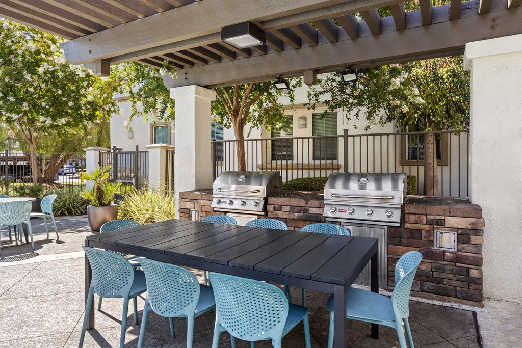 a patio with a table and chairs and two bbq grills