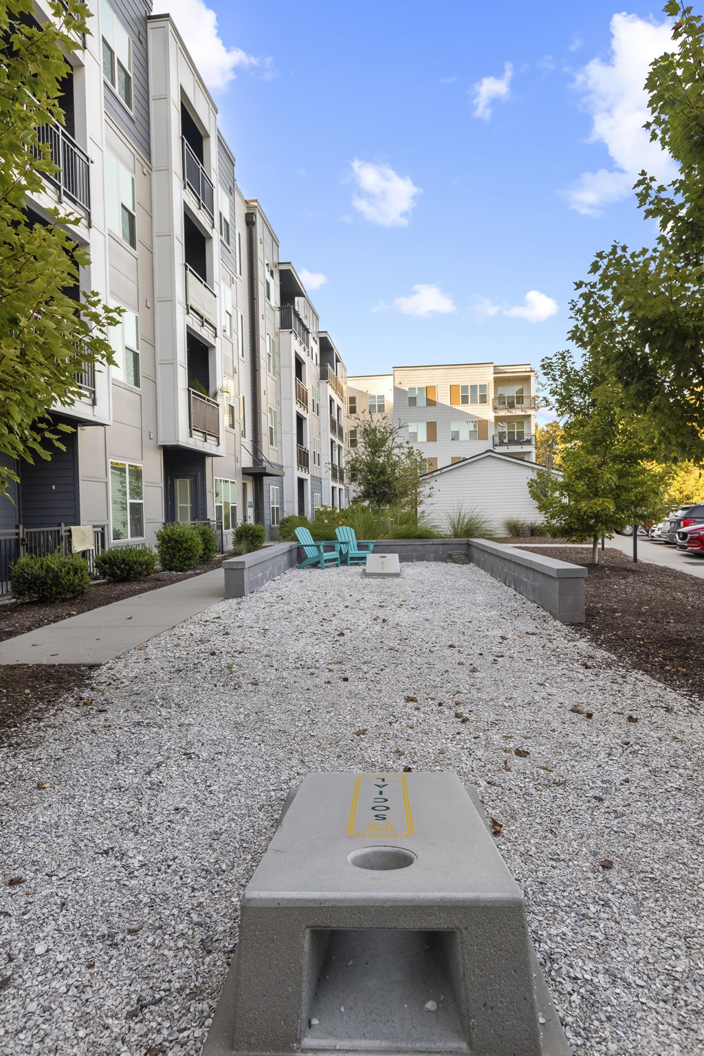 A concrete bench with a yellow line on it is in the middle of a gravel path.