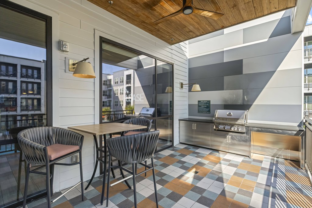 A patio with a table and chairs and a grill.