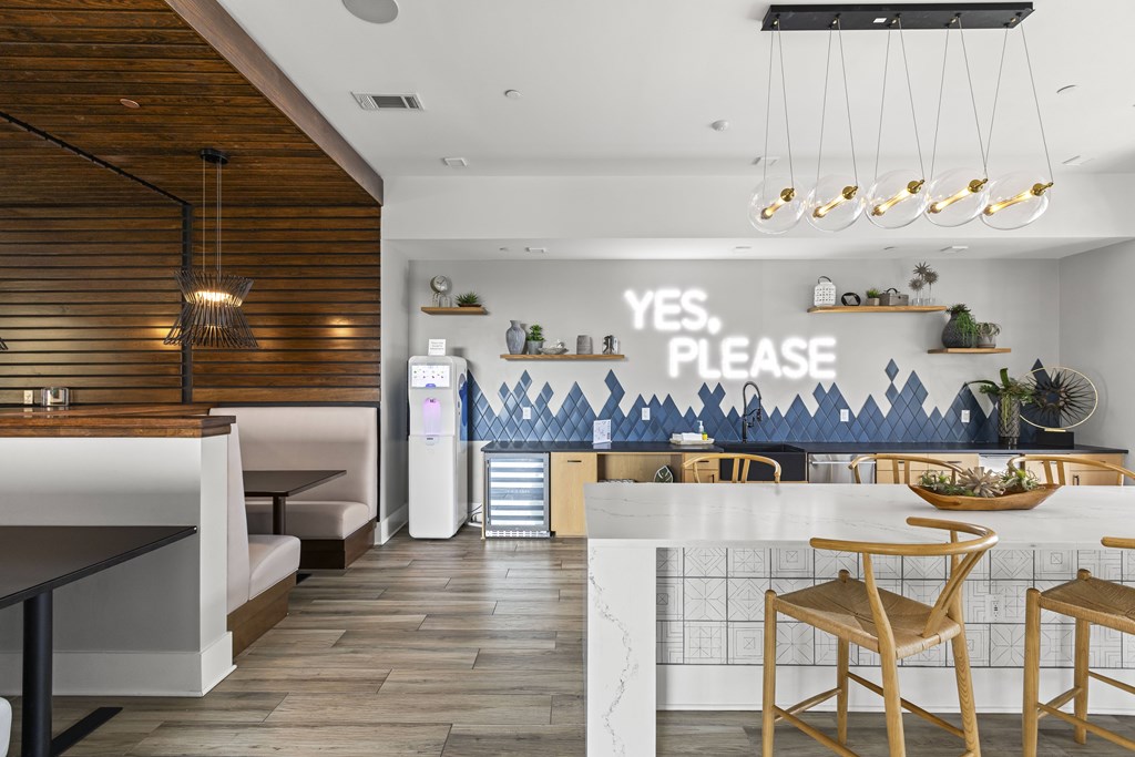 A modern kitchen with a white counter and wooden chairs.