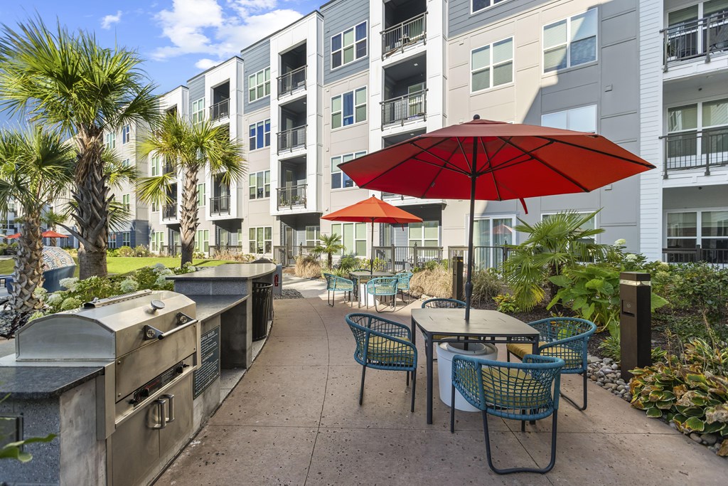 A patio with a table and chairs and a red umbrella.