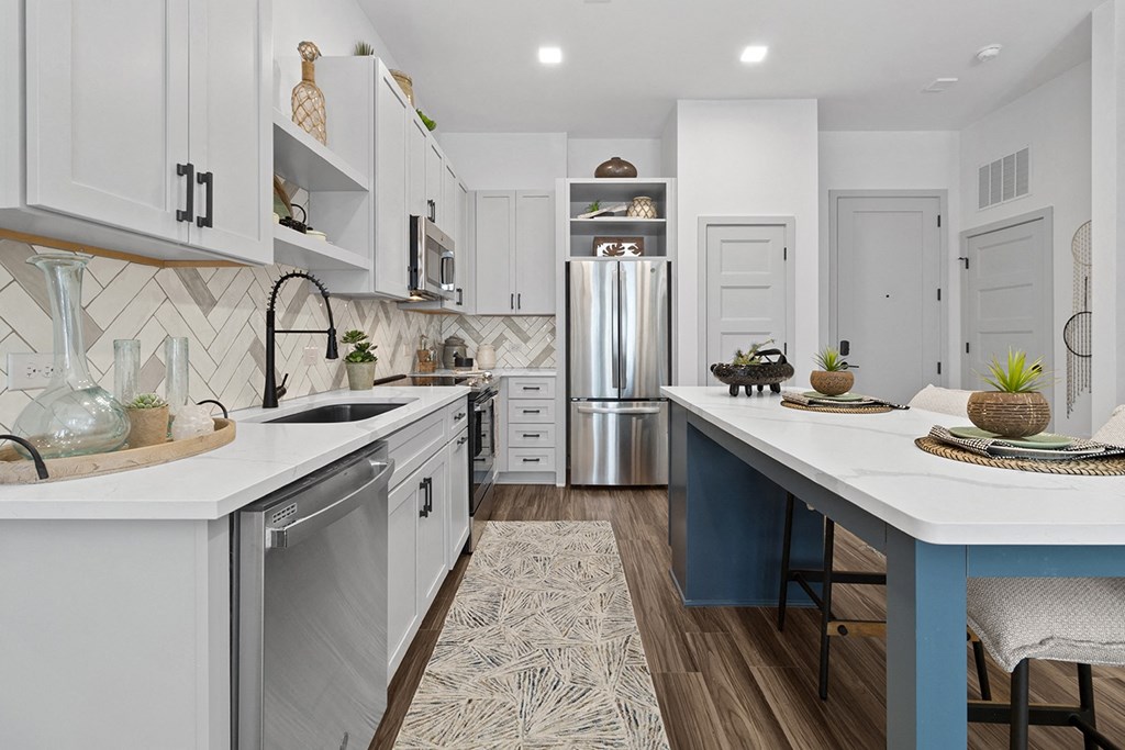an open kitchen with a large island and a stainless steel refrigerator