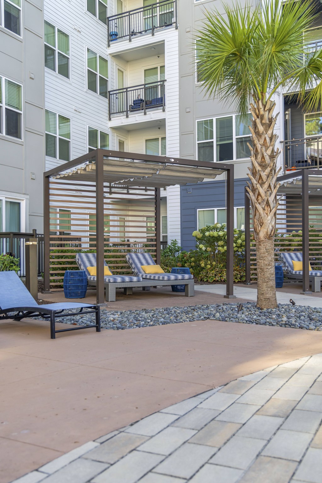 A patio with a bench and a tree in front of a building.