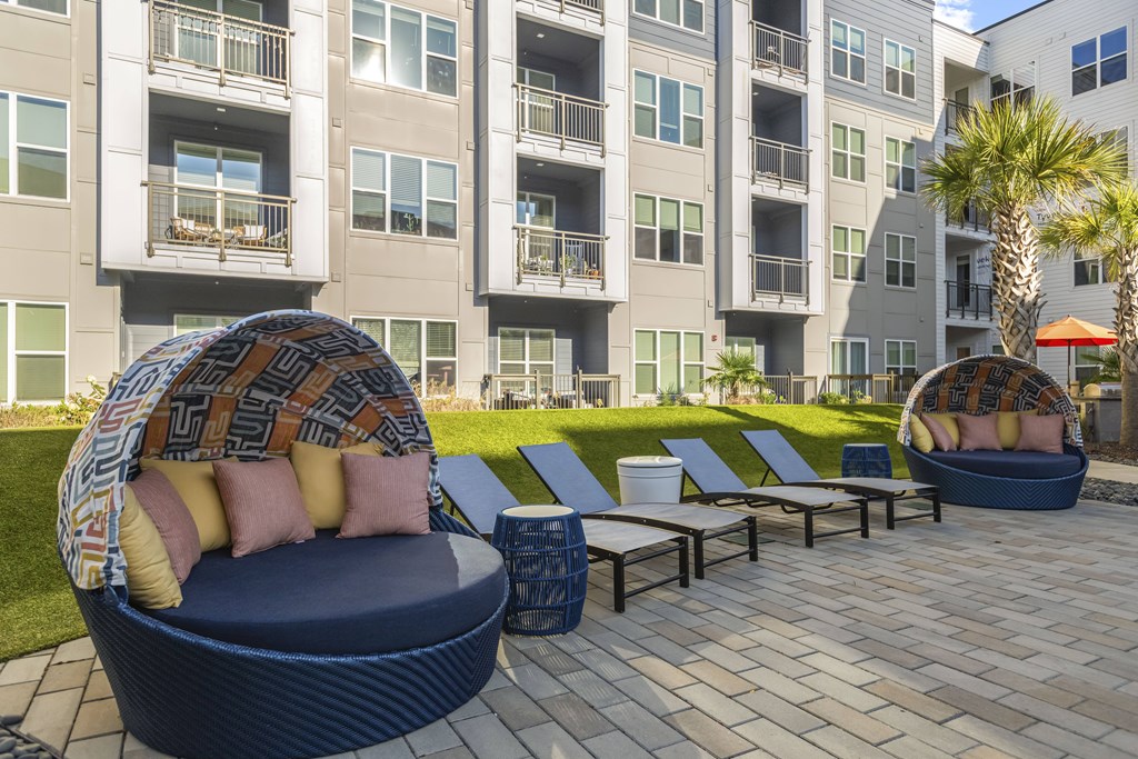 A blue couch with a blanket on it is in the foreground of a patio area with a building in the background.