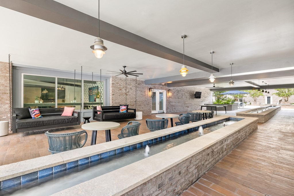 a seating area with tables and chairs and a pool in the middle of the room