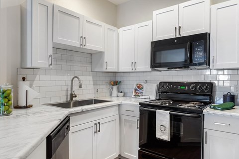 a kitchen with white cabinets and black appliances and a sink