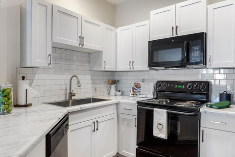 a kitchen with white cabinets and black appliances and a sink