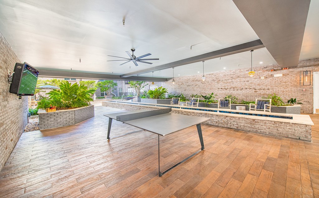 a ping pong table sits in the middle of a room with a brick wall