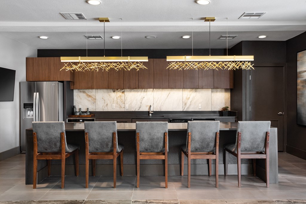a modern kitchen with a long island with chairs and a counter top