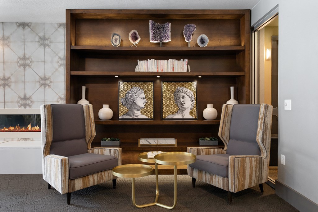 a living room with two chairs and a shelf with artwork and a fireplace