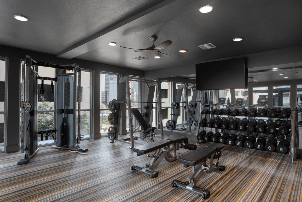 a workout room with weights and a television and windows