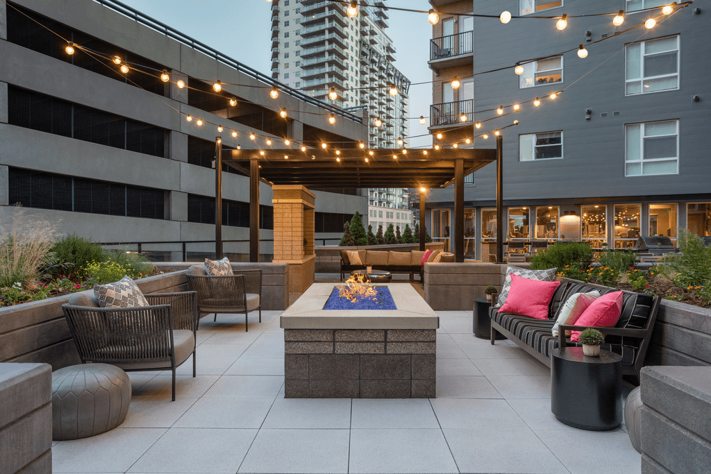 an outdoor patio with a fire pit and seating under lights