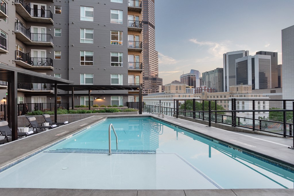 the pool on the rooftop of an apartment building with the city in the background