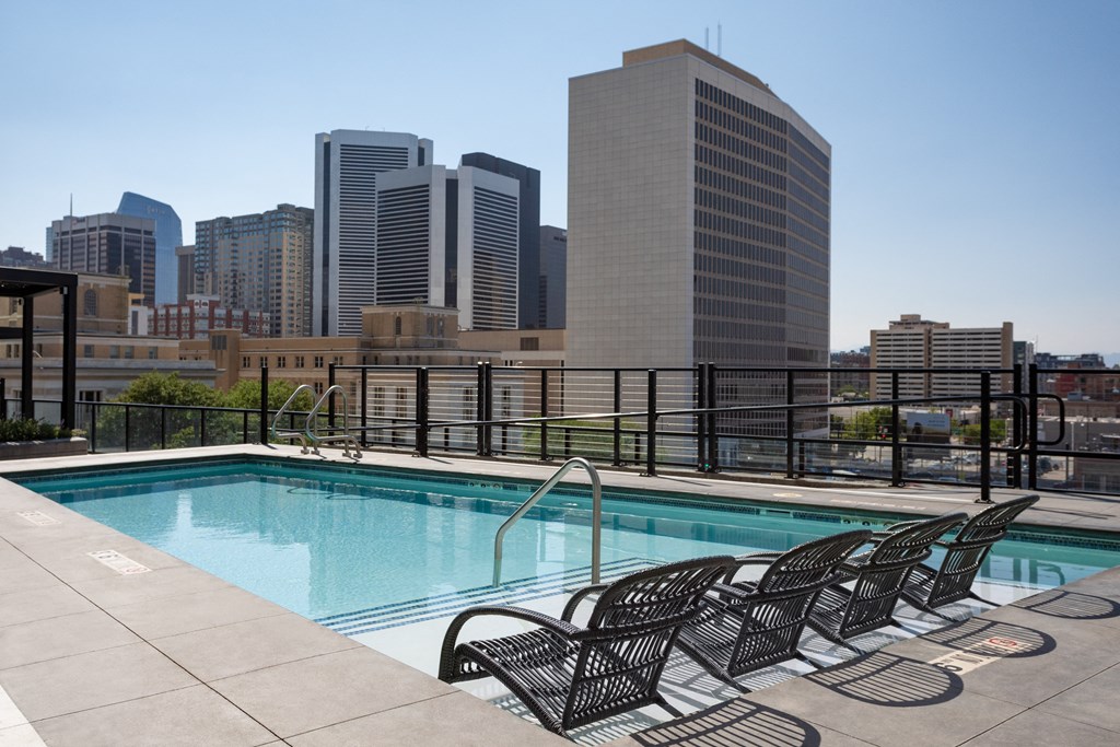 a pool on the rooftop of a building with the city in the background