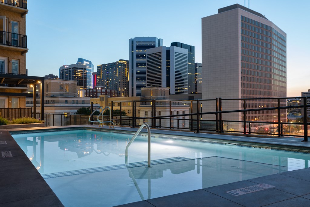 a pool on the roof of a building with a city in the background