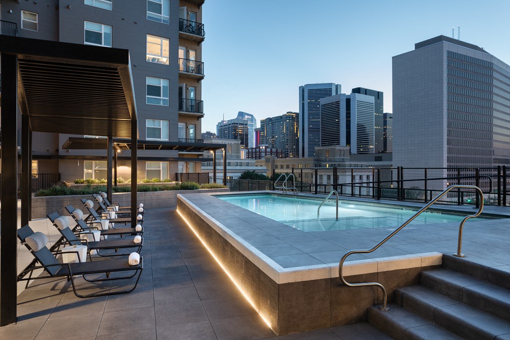 a pool on the rooftop of a building with a city in the background