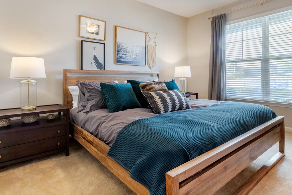 a bedroom with a large window and a bed with a blue comforter