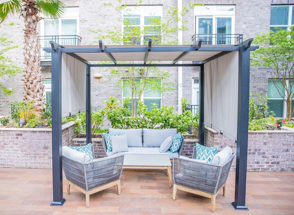 a pergola with two chairs and a couch on a patio