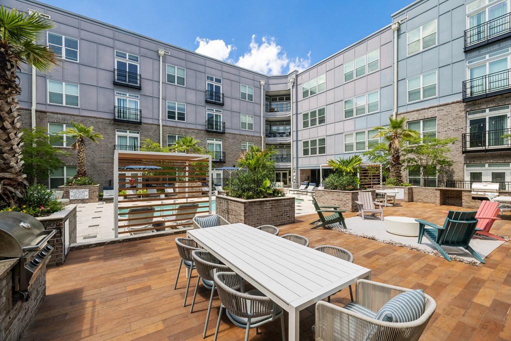 a patio with a white table and chairs and a barbecue grill
