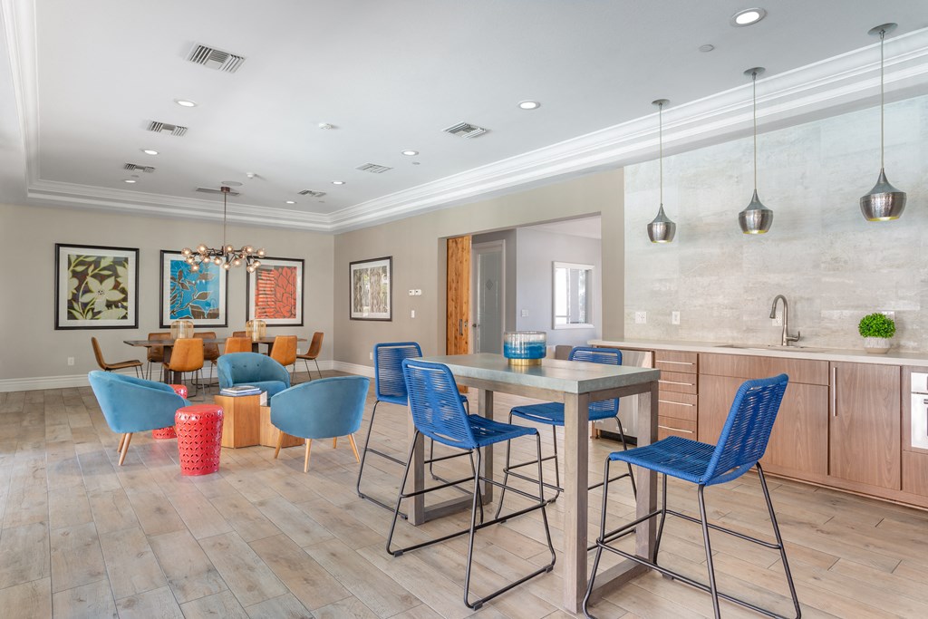 a seating area with a table and chairs and a kitchen with a sink and a counter