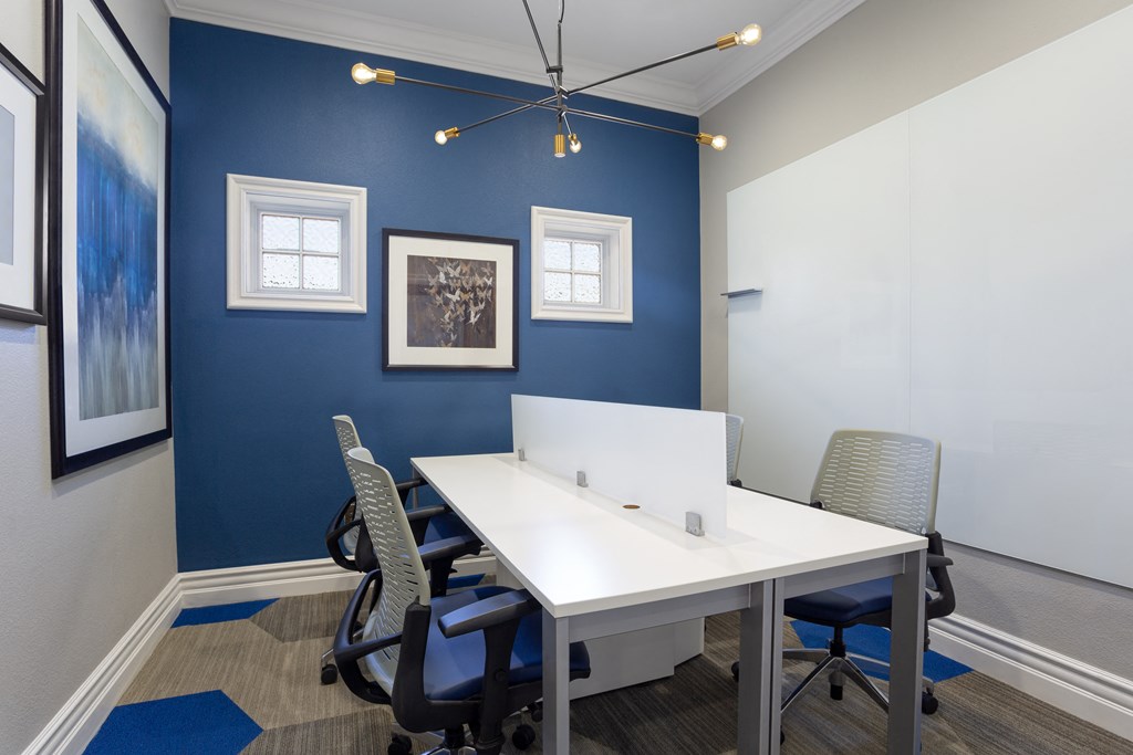 a shared workspace with a white desk and blue chairs