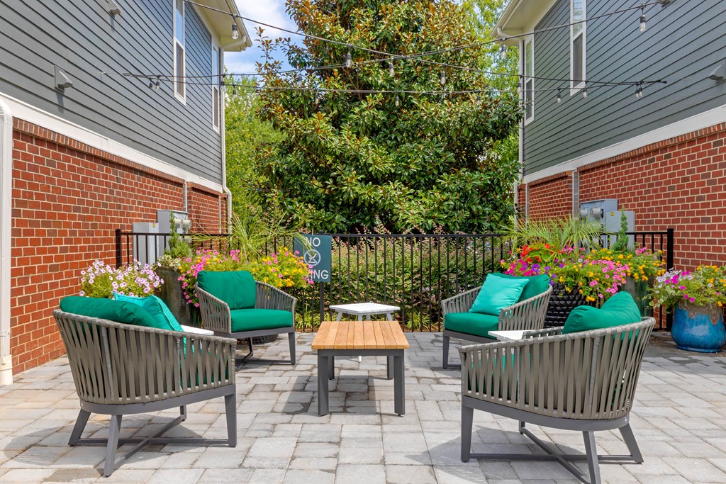 a patio with chairs and a table in front of a brick building