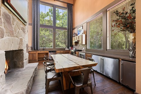 A dining room with a stone fireplace and a wooden table.