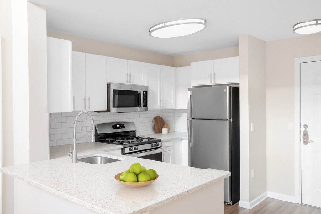 a kitchen with white cabinets and a white counter top with a bowl of fruit on it