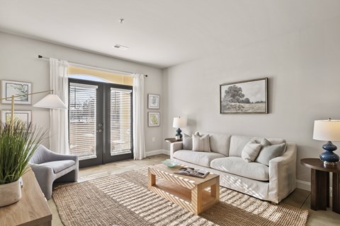 A living room with a grey couch, a coffee table, and a painting on the wall.