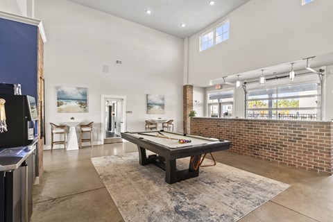 A room with a pool table and a brick wall.