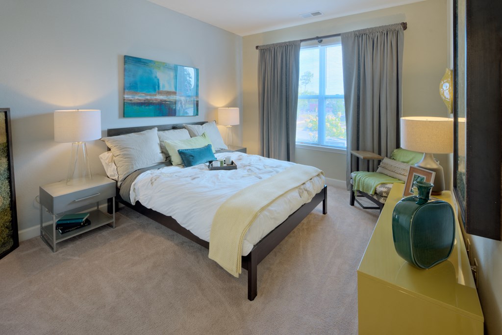 a bedroom with a large bed and a chair in front of a window