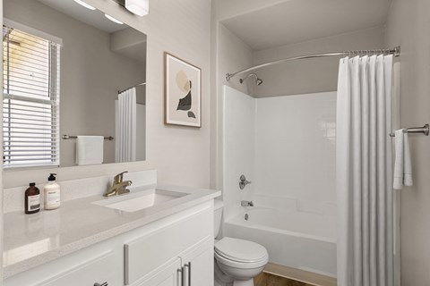 a bathroom with a white sink and toilet next to a white bathtub with a shower curtain