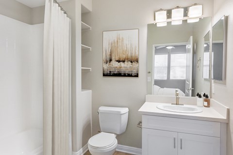 a bathroom with a white sink and toilet and a white shower curtain