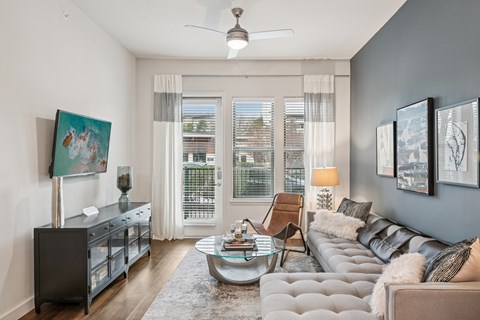 A living room with a grey couch, a coffee table, and a painting on the wall.