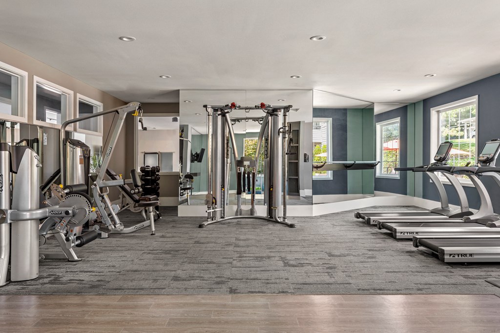 a gym with treadmills and other exercise equipment in a room with windows