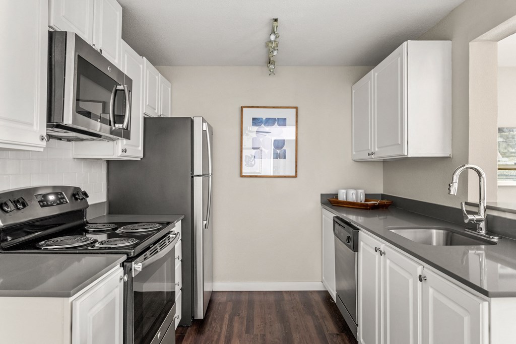an apartment kitchen with stainless steel appliances and white cabinets
