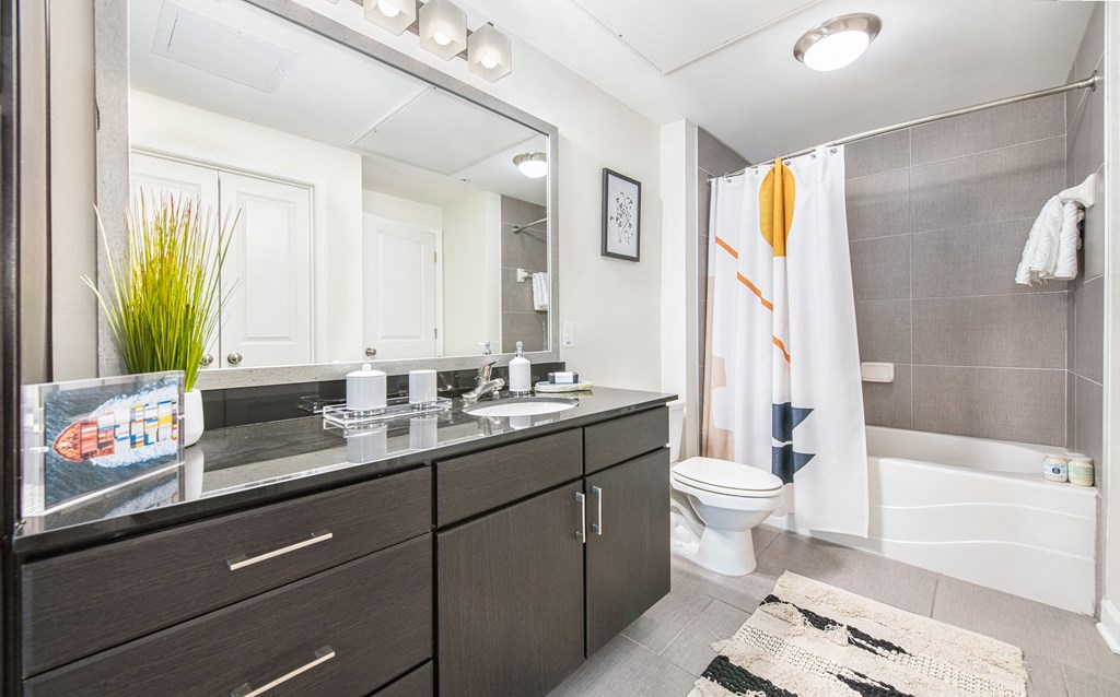 a bathroom with gray cabinets and a white shower curtain