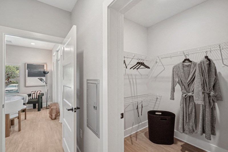 a closet with clothes hanging on a rack and a bathroom with a sink
