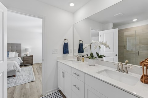 bathroom with a white sink, a mirror, and a bedroom in the background.