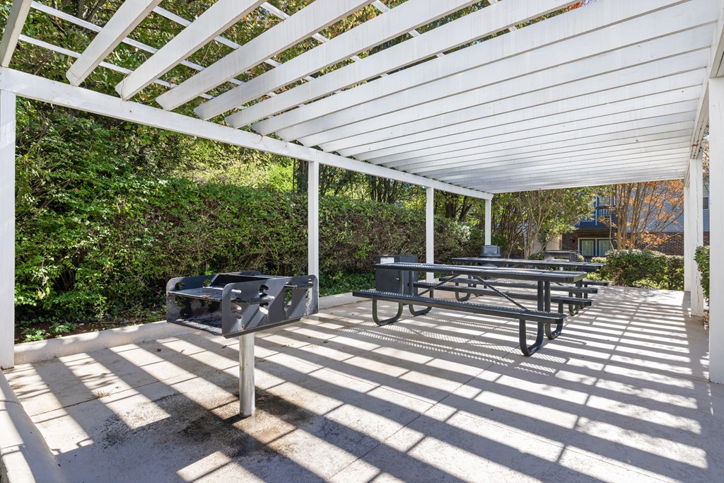 A white pergola with a bench and mailbox underneath it.