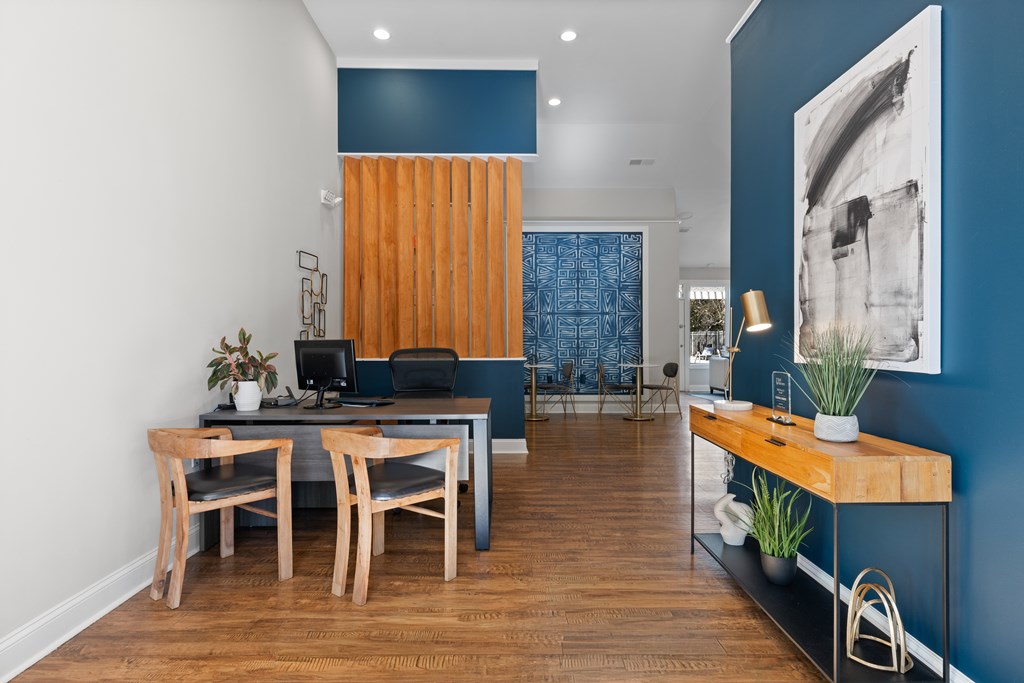 A room with a desk, chairs, and a blue wall.