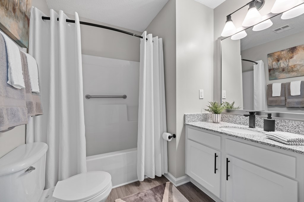 A white bathroom with a toilet, sink, and shower.