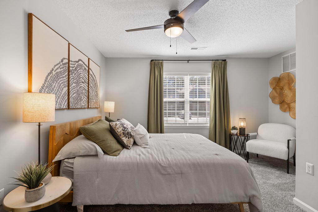 A bedroom with a bed, a ceiling fan, and a chair.