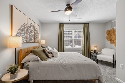 A bedroom with a bed, a ceiling fan, and a chair.