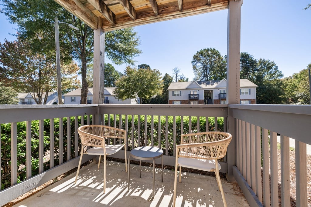 A wooden porch with two chairs and a table.