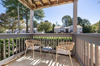 A wooden porch with two chairs and a table.