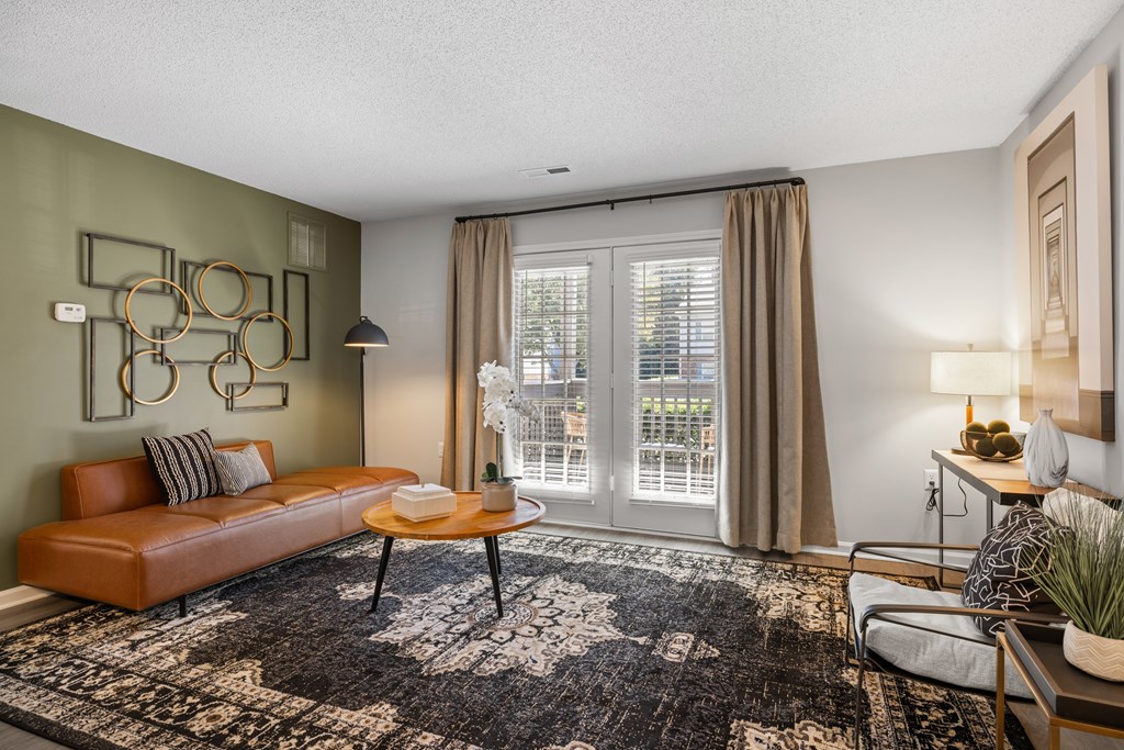A living room with a brown leather sofa, a coffee table, and a rug.