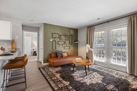 A living room with a brown leather couch and a black and white patterned rug.